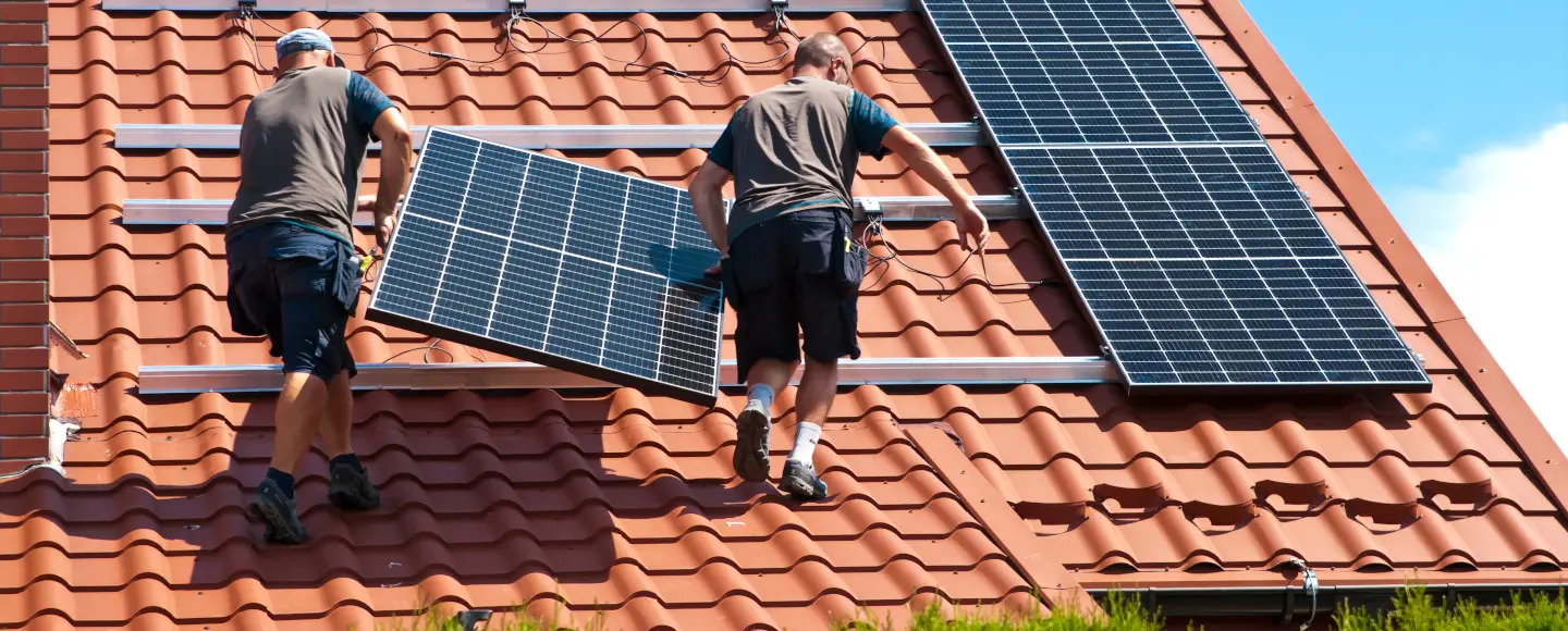 Un homme installe des panneaux solaires sur le toit d'une maison