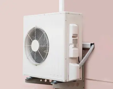 unité extérieure d'une pompe à chaleur air/eau sur un mur rose