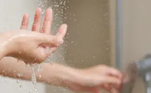 mains qui vérifie la température de l'eau de la douche
