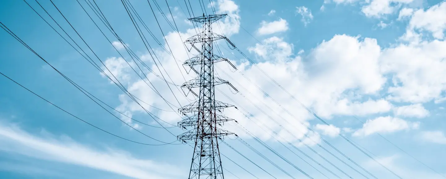 Une ligne électrique à haute tension devant un ciel bleu avec nuages