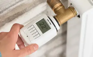 mains sur un chauffage qui règle la température