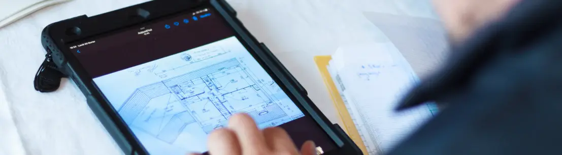 personne utilisant une tablette qui affiche le plan d'une maison