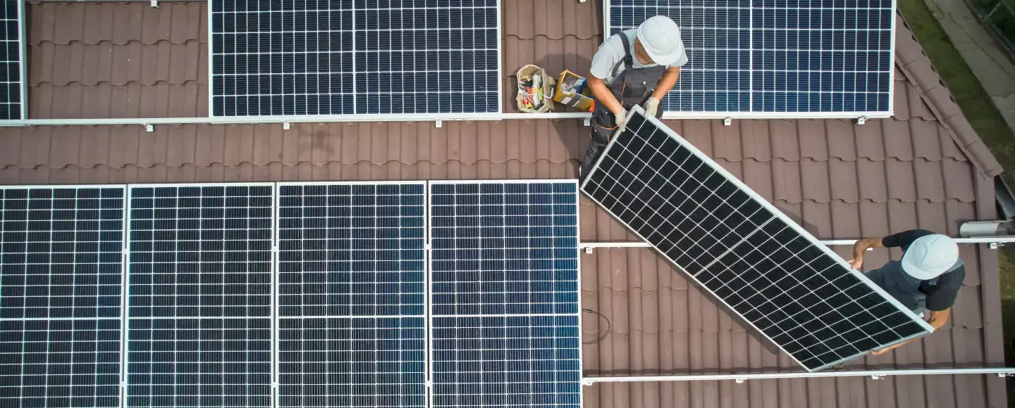 deux personnes installent des panneaux solaires sur un toit