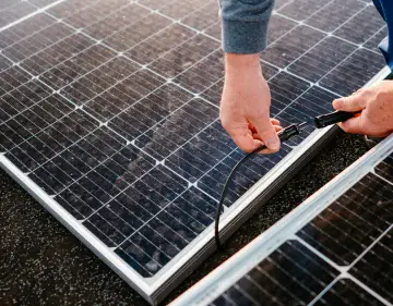 Une personne relie les cables d'un panneau solaire