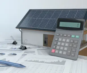 maquette maison grise avec des panneaux solaire et une calculatrice sur des papiers