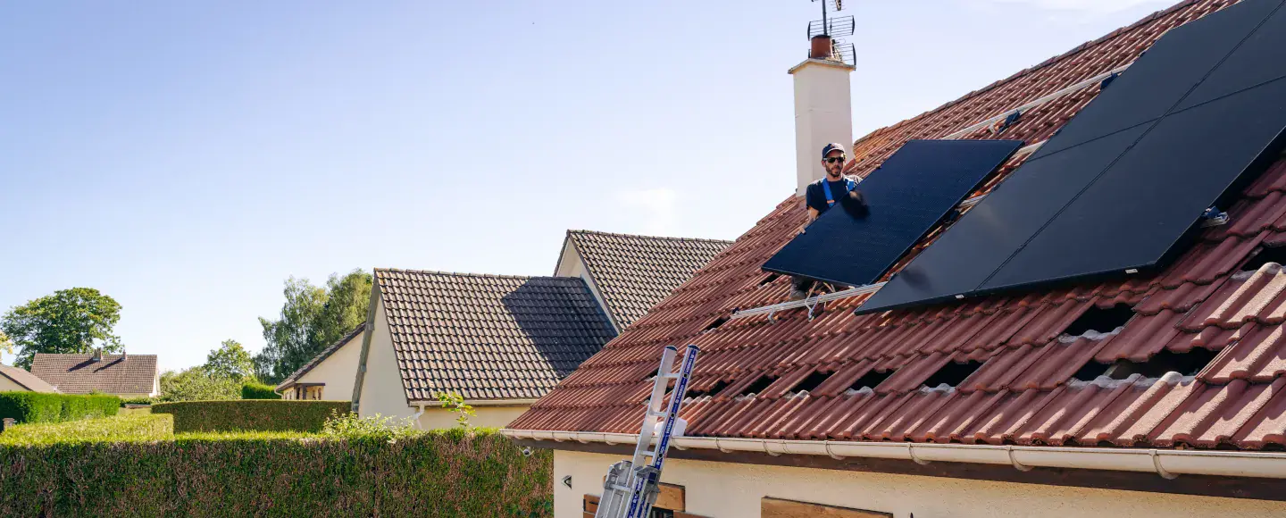 Un homme installe des panneaux solaires photovoltaïques sur le toit d'une maison