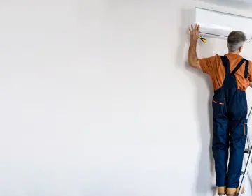 deux personnes installent une pompe à chaleur air air dans une maison