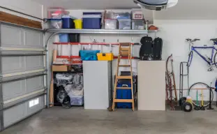 garage d'une maison avec des murs blancs, des outils de bricolage, une échelle en bois et un vélo bleu