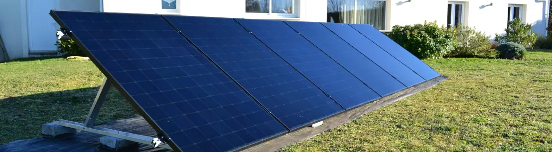panneaux solaires au sol avec une maison sur une pelouse verte