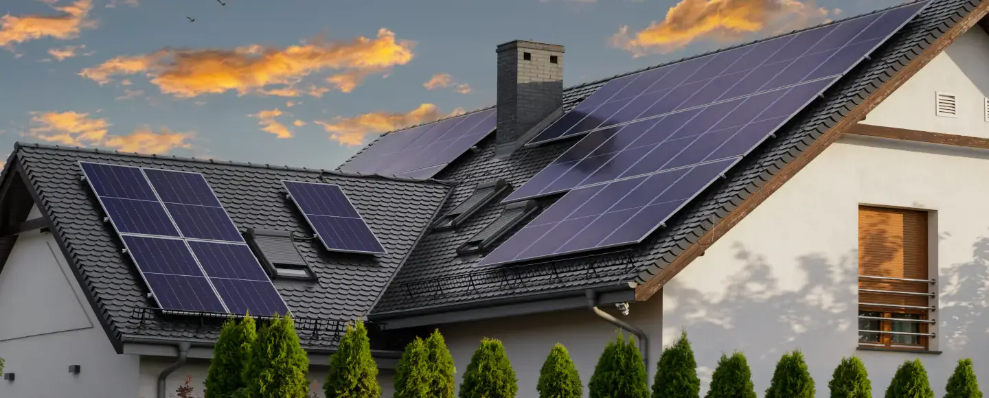 Une maison avec des panneaux solaires sur le toit et un coucher de soleil