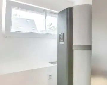 chauffe eau thermodynamique gris dans une salle avec une fenêtre rectangulaire