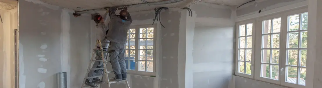 L'intérieur d'une maison en rénovation énergétique globale avec deux ouvriers
