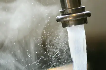 eau chaude sortant d'un robinet avec de la vapeur