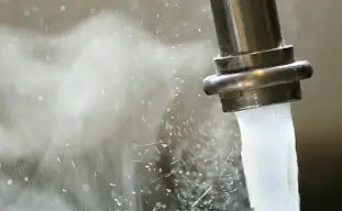 eau chaude sortant d'un robinet avec de la vapeur